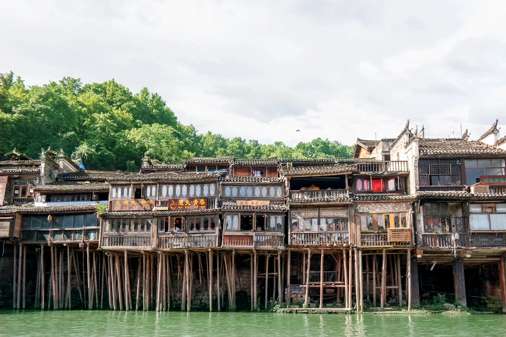 Mountain village of wooden Chinese dwellings built on steep slopes with misty peaks behind
