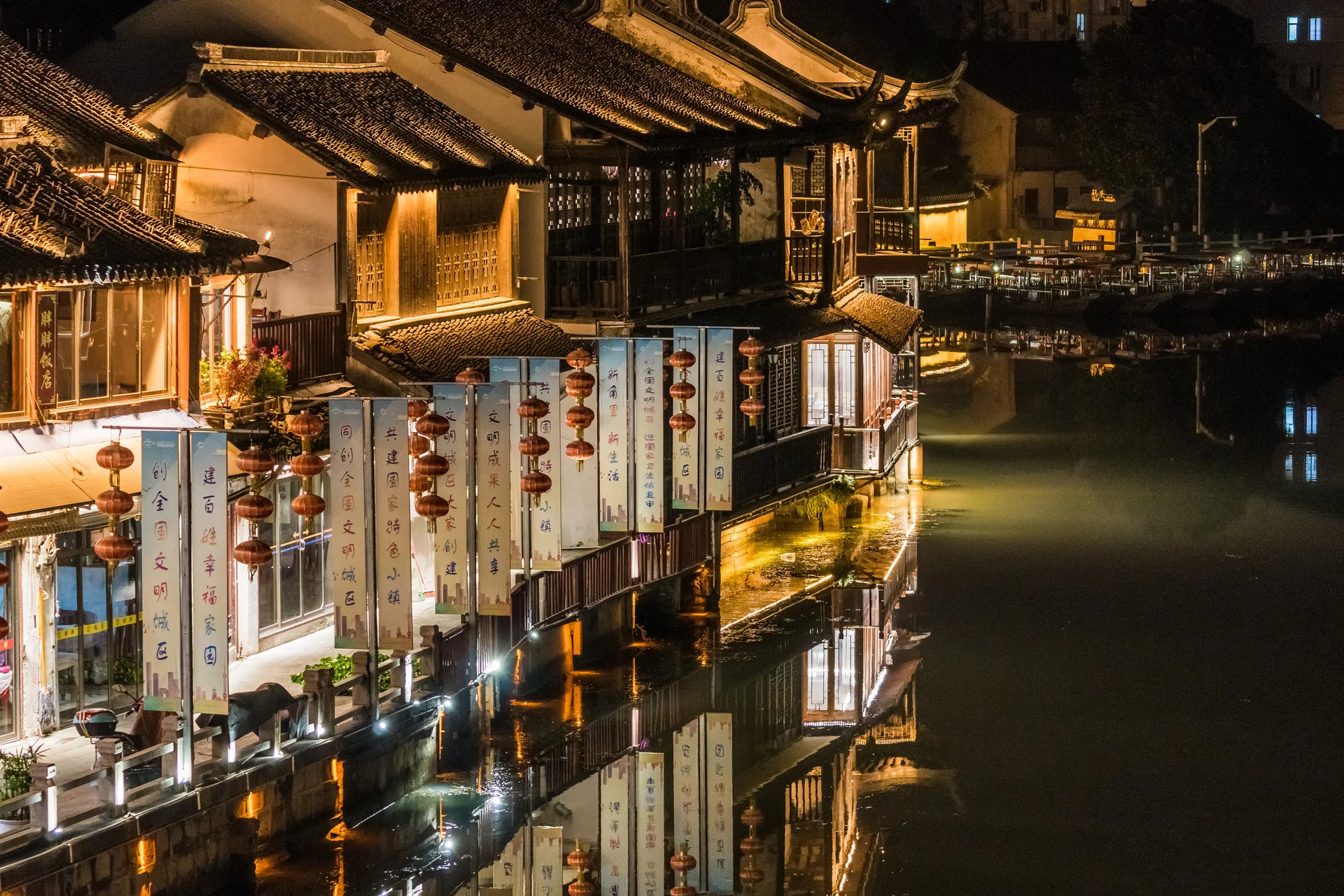 Panoramic Jiangnan water town with canal, stone bridge, and whitewashed riverside houses