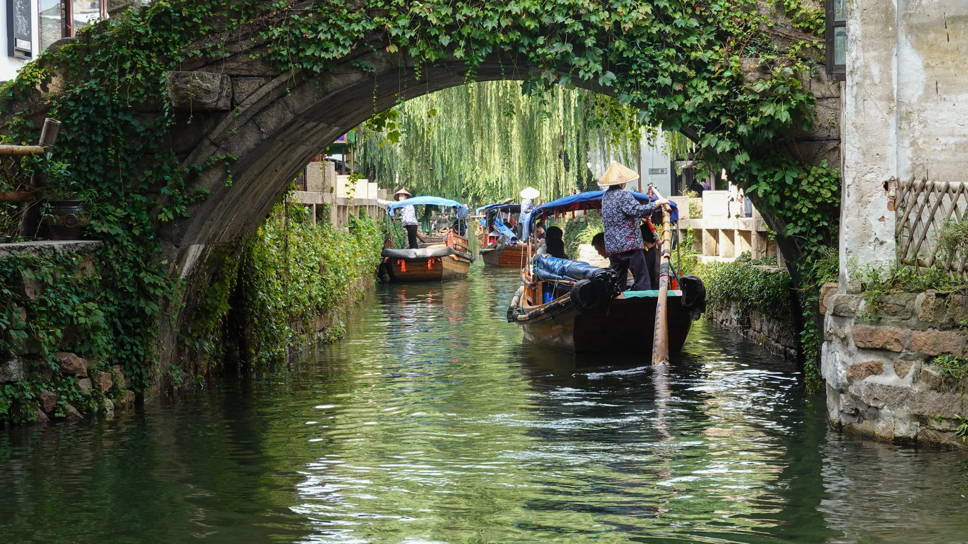 Narrow canal in a Jiangnan water town lined with whitewashed houses and small wooden boats